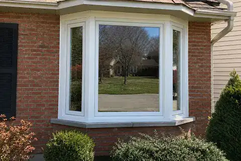 White bay window assembly with casement side units on a brick home exterior.