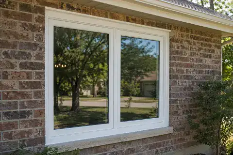 White vinyl casement-style replacement windows installed on a brick home exterior.